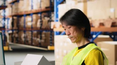 Dağıtımdan önce karton kutuları ve paket izleme, işleme işleme için awb etiketlerini doğrulayan işçiler. Elektronik ticaret deposunda endüstriyel raflarla çalışan bir adam. Kamera B.