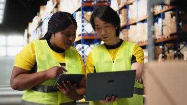 Büyük ölçekli depo ekibi e-ticaret siparişi işlemlerini yönetiyor, ambalajdaki büyük sanayi raflarına yerleştirilen paketleri kontrol ediyor. Yeleklerdeki çalışanlar kutulara bakarlar. Kamera B.