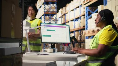 Siyahi kadın müşteri destek memuru müşterilerle sevkiyat detayları hakkında konuşuyor, yardım hattında yanlış adres karışıklığına yardım ediyor. Kadın siparişi çözer, havayolu faturalarını onaylar. Kamera A.