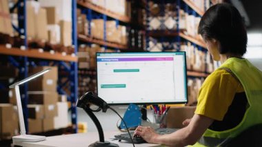 Asyalı erkek işçi sevkiyat etiketlerini ve dağıtım merkezindeki takip numaralarını tarıyor, tatmin merkezinde sipariş yönetimini garantiliyor. Ulaşım detayları için tarayıcı kullanıyor. Kamera B.