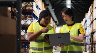 Afro-Amerikan ve Asyalı işçiler, dizüstü bilgisayardaki stokları inceleyen ve siparişleri düzene sokan büyük bir markanın ürünlerini işletiyorlar. Müşteriler için profesyonel hızlı teslimat. Kamera B.