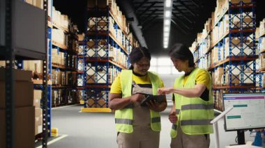 Afro-Amerikan ve Asyalı insanlar online siparişleri ve havayolu faturalarını yönetiyor, ürünleri paketlemeden önce envanteri kontrol ediyorlar. Büyük ticari perakende operasyonları. Kamera A.