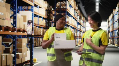 Afro-Amerikan ve Asyalı ekipler kargo mallarını canlı yayında sunuyorlar. Rafların yakınındaki endüstriyel depoda bir video kaydı yapıyorlar. Büyük iş reklamları için içerik. Kamera A.