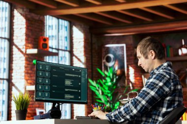 Masada oturan adam, AI LLM sohbet robotu yazılımıyla modern merkez ofiste konuşuyor. Parlak apartman odasındaki bilgisayarda büyük dil programı ile iletişim kuran kişi