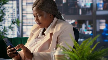 Afrikalı Amerikalı şirket müdürü molasında mesajlar yolluyor. Organizasyon projesinin geliştirilmesinden memnun. Kadın CEO, ağdaki çalışanlarıyla görüşlerini paylaşıyor. Kamera A.