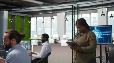 Ofisteki mutlu kadın mühendis yapay zeka senaryoları kullanarak tekrarlanan görevler yapıyor. Jolly Afro-Amerikan Geliştirici Yapay Zeka kullanarak uzun metrajlı uygulamayı hızlandırıyor, kamera A