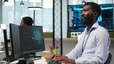 Bilgisayar bilimcisi yapay zekayı performansı ve tahminleri optimize etmek için kullanıyor. Ofis eğitim makinesinde çalışan Afrikalı Amerikalı işçi bilgisayar, kamera A kullanarak modeller öğreniyor.