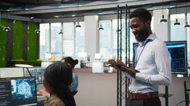 Happy programcı yazılım uygulamaları tasarlıyor ve geliştiriyor, performans ve ölçeklenebilirlik için kodu optimize ediyor. Dar geçitleri çözmek için tablet kullanan keyifli bilişim uzmanı, kamera A