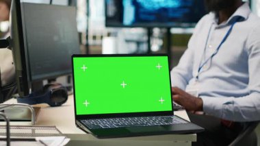 Ofis arkadaşlarının yanındaki teknisyen yeşil ekran laptopunu kullanarak yapay zeka otomasyonunu entegre ederek yazılım uygulamaları geliştiriyor. Bilgi İşlem uzmanı, A kamerası ve maket defteri ile hata ayıklama uygulamaları yapıyor.