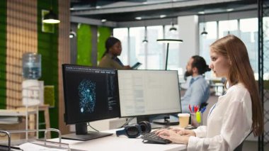 Küçük dev üretici yapay zeka makinesini test ediyor algoritmaları öğreniyor ve iş yerinde müzik dinliyor. Kulaklık takan genç bir kadın yapay zeka ile verimliliği artırıyor.