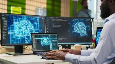 Ofisteki yönetici yapay zeka makinesinin birden fazla aygıt üzerinden görevleri çalıştırmayı öğrenmesine ve ekranlardaki ilerlemeyi izlemesine güveniyor. IT uzmanı yapay zeka modelleri geliştirmek için sinirsel ağlar kullanır, kamera A