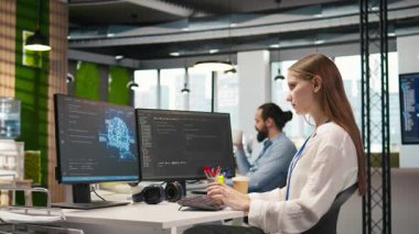 Ofisteki genç bayan programcı yapay zeka ölçümlerini inceliyor, müzik dinliyor, performans göstergelerini izliyor. Küçük Dev kulaklık takıyor sinirsel ağları ayarlıyor PC 'deki araçları kullanıyor, kamera A