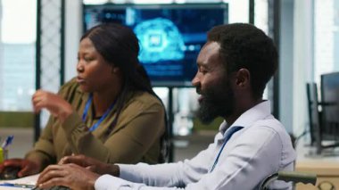 Engelli neşeli teknisyen ve iş arkadaşı yazılımın hata ayıklama algoritmalarını kodlarken sohbet ediyor. Bilgisayar, kamera A kullanarak iş arkadaşı ve tekerlekli sandalye bilişim uzmanı.