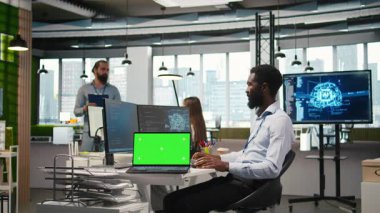 İş analizleri için yapay zeka modelleri geliştiren yeşil ekran dizüstü bilgisayar kullanan bir ofis programcısı. Yapay zeka tahminleri için simülasyonları çalıştıran bir bilgisayar uzmanı, kamera A