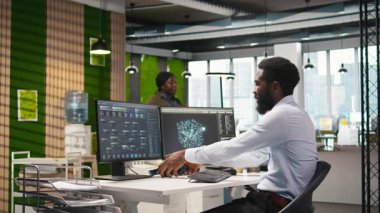 Yazılım geliştiricisi üretken yapay zeka makinesini test ediyor algoritmaları öğreniyor ve iş yerinde müzik dinliyor. Kulaklık takan Afrikalı Amerikalı adam yapay zeka modelinin üretkenliğini ölçüyor, kamera A