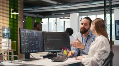 Arkadaş canlısı ekip lideri, yazılım sorunlarını çözmek ve sistem istikrarını geliştirmek için genç mühendis yapay zeka algoritmalarını kodlamaya yardım ediyor. Yardımcı yönetici, teknoloji firması ofisinde gülümseyen stajyere yardımcı oluyor, kamera A