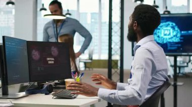 Ofisteki programcı kritik hata uyarısını düzeltmek için iş arkadaşlarından yardım istiyor. BT çalışanı ve meslektaşları, bilgisayar hatasının nasıl düzeltileceği konusunda fikir alışverişinde bulunuyorlar.