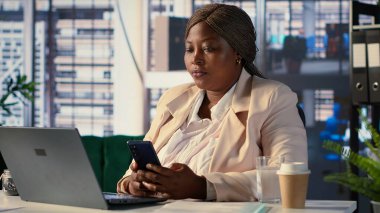 Afrika kökenli Amerikalı girişimci iş molasında mesaj atıyor, kariyer gelişmelerinden memnuniyet duyuyor. Girişim ağındaki güncellemeler için çalışanlarla sohbet ediyorum. Kamera A.