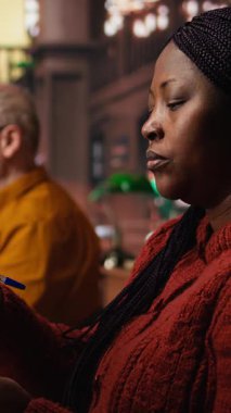 Dikey Afrikalı Amerikalı kadın kitap okuyor ve ders notlarını çalışma odasında tamamlıyor, tezine hazırlanıyor ve halk kütüphanesinde arşivlenmiş akademik materyalleri araştırıyor. Kamera A.