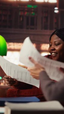 Dikey video kadın kişi odaklı bir ifade ile önemli fikirlerin altını çiziyor, üniversite kütüphanesinde dosya okuyor. Diplomasını tamamlamak için akademik araştırma. Kişisel gelişim. Kamera B.