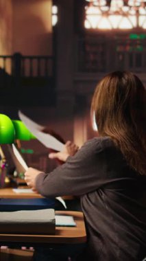 Dikey video kadın kişi odaklı bir ifade ile önemli fikirlerin altını çiziyor, üniversite kütüphanesinde dosya okuyor. Diplomasını tamamlamak için akademik araştırma. Kişisel gelişim. Kamera A.