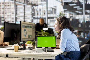 Genç yönetici, projenin geliştirilmesi için kurumsal çözümler üzerinde çalışarak masadaki izole görüntülerin yanında bilgi grafikleriyle çalışıyor. Analist çalışma istasyonunda çevrimiçi verileri gözden geçiriyor.