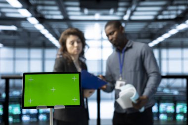 Veri merkezinde sistem yöneticileri tarafından kullanılan yeşil ekran laptop süperbilgisayarları denetliyor, ağ topolojilerini güncelliyor. Sunucu çiftliğindeki kadın ve erkeğin yanındaki maket defterini kapat