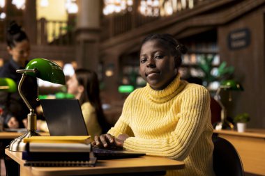 Kütüphanede bir okul ödevi üzerinde çalışan, yeni edebiyat sınıfı makalesi için beyin fırtınası yapan bir öğrenci. Afrikalı Amerikalı kız akademik büyüme ve üretken öğrenimi vurguluyor.