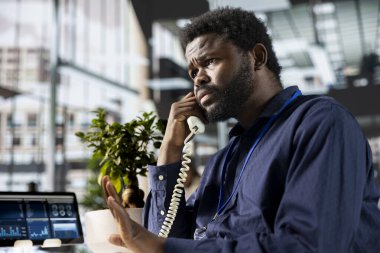 Afrika kökenli bir Amerikalı iş arkadaşından şirket brifingi, ağ oluşturma ve fikir alışverişinde bulunmak için bir sabit telefon görüşmesine cevap veriyor. İş geliştirme görevleri.