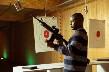 Antrenman yapan birinin portresi, tüfeği cephaneyle doldurmak, güvenlik gözlüğü takmak. Atış poligonunda silahlı bir adam yaralanmayı önlemek için koruyucu giysi giyiyor ve şarjör takıyor.