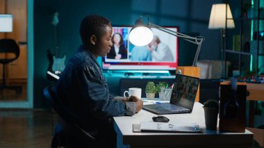 İş görüşmesi sırasında apartman ofisindeki video görüşmesinde uzaktan çalışan meslektaşlarını selamlıyor. Uzaktan video konferansa katılan serbest meslek sahibi bir kadın evde kamera A iken tele konferansa katılıyor.