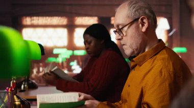 Üniversite kampüs kütüphanesindeki tez projesini araştıran olgun bir kız öğrenci akademik başarı için ilham ve adanmışlığı gösteriyor. Evrak işleriyle uğraşıyorum. Kamera B.