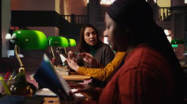 Afrikalı Amerikalı bir kadın insanlardan kütüphanede sessiz olmalarını istiyor. Gürültü ve saygısızlıktan dolayı kitap okumaya çalışıyorlar. Kütüphane adabı için kibarca bir istekte bulunuyorum. Kamera A.