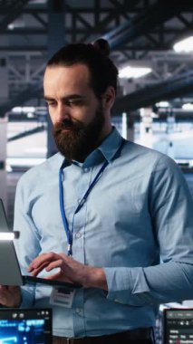 Sinir ağı AI LLM görüntülemesini izlemek için dizüstü bilgisayar kullanan dikey video veri merkezi teknisyeni. Bilgi teknolojisi uzmanı sunucuların öğrenme makinesini denetlemek için dizüstü bilgisayar kullanıyor.