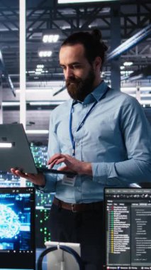 Sinir ağı AI LLM görüntülemesini izlemek için dizüstü bilgisayar kullanan dikey video veri merkezi teknisyeni. Bilgi teknolojisi uzmanı sunucuların öğrenme makinesini denetlemek için dizüstü bilgisayar kullanıyor.