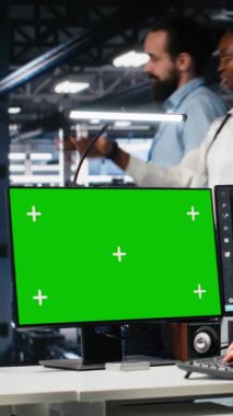 Yapay zeka sistemlerini kontrol eden dikey video veri merkezi teknisyeni. Sunucu merkezindeki yeşil ekran bilgisayarda yapay zeka kullanan teknoloji uzmanı, kamera A