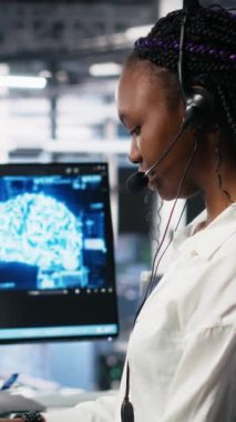 Kullanıcı teknik desteği sağlamak için yapay zeka asistanını kullanan dikey video veri merkezi bilgisayar bilimcisi. Sunucu çiftliğindeki Afrikalı Amerikalı kadın yapay zekanın yardımıyla canlı destek aramalarını yönetiyor.