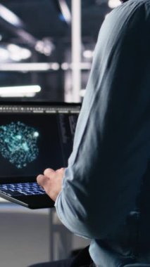 AI LLM sohbet robotunu kullanarak sinirsel ağı izlemek için dizüstü bilgisayar kullanan dikey video veri merkezi programcısı. Sunucuların makine öğrenmesini denetlemek için bilgisayardaki yapay zekayı kullanan işçiler, kamera