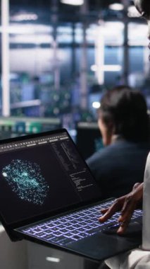 Veri merkezi teknisyeninin AI LLM görselleştirmesini izlemek için tablet kullanan dikey videosu. İşçi, sunucuların öğrenme makinesini denetlemek için aygıt üzerinde büyük dil modeli kullanıyor