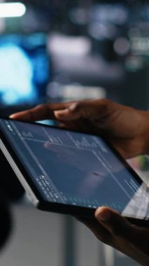 Otomasyon kodlarını gözden geçirmek için tablet kullanan veri merkezi mühendisinin dikey görüntüsü. Aygıt kullanan sunucu tarım sistemi yöneticisi hata ayıklama işlemleri ve kamera için hata günlüklerini izliyor