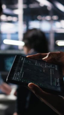 Otomasyon kodlarını gözden geçirmek için tablet kullanan veri merkezi mühendisinin dikey görüntüsü. Aygıt kullanan sunucu tarım sistemi yöneticisi hata ayıklama işlemleri ve kamera için hata günlüklerini izliyor