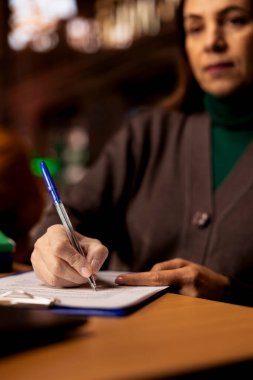 Akademik arşiv belgeleri ve kitaplarla çevrili üniversite diploması için ders notları yazan ve inceleme yapan odaklanmış bir kadın. Çalışma alanında sakin bir atmosfer. Kapat..