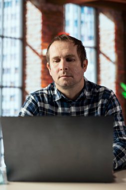 İşçi masadaki veri tablolarını analiz ediyor, istatistiksel grafikleri yorumluyor, eğilimleri tanımlıyor, analitik raporları derliyor, bilgiyi işlemek ve görselleştirmek için veri analiz yazılımı kullanıyor