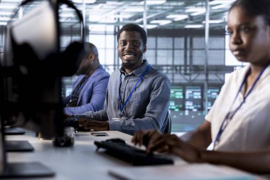 Veri merkezinin elektronik ömrünü uzatmak ve ara vermekten kaçınmak için yıllık check-up yapan meslektaşlarının yanında neşeli bir yönetici. Sunucu odasındaki mutlu mühendisler sunucu altyapı bileşenlerini izliyor