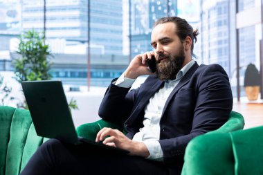 CEO, dizüstü bilgisayarındaki mali raporları incelerken yatırımcılarla önemli bir telefon görüşmesi yapıyor ve yönetiyor. İş yerinde iş hayatında stratejik karar alma.