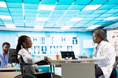 Afrika kökenli Amerikalı pratisyen ve engelli bir kız detaylı bir check-up yaptırıyor, hastalıkların önlenmesi için profesyonel bakım ve sağlık uygulamalarını vurguluyor. Kronik bozukluk..