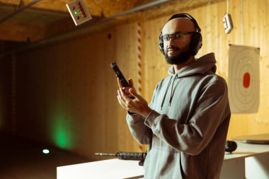 Orta Doğulu bir adamın ev içi atış poligonundaki portresi seçmeler için kiralık silah sunuyor, antrenman yapıyor. Arap çaylaklar atış talimi yapıyor.