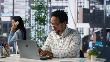 Masasındaki erkek ofis yöneticisi proje yönetimi ve finansal planlama ile meşgul. İşletme uzmanı, çok önemli organizasyonel tarihleri ve verimliliği karşılamak için bilgisayar üzerinde çalışıyor. Kamera A.