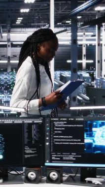 Veri merkezi mühendislerinden oluşan dikey video ekibi evrakları inceliyor ve veri tabanlarını analiz etmek için derin öğrenme algoritmaları kullanıyor. Çok ırklı sunucu çiftliğindeki çalışanlar veri örneklerini tanımak için yapay zeka kullanıyorlar