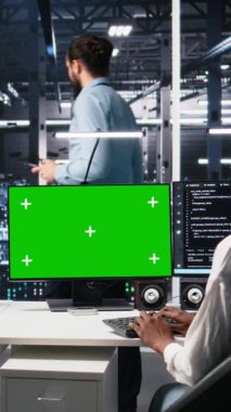 Veritabanı inceleme merkezindeki kadın teknisyen ve iş arkadaşı izole ekran bilgisayarındaki yapay zeka tanılarını inceliyor. Bilişim uzmanı ve meslektaşı krom anahtar bilgisayar kullanarak yapay zeka sistemlerini optimize ediyor